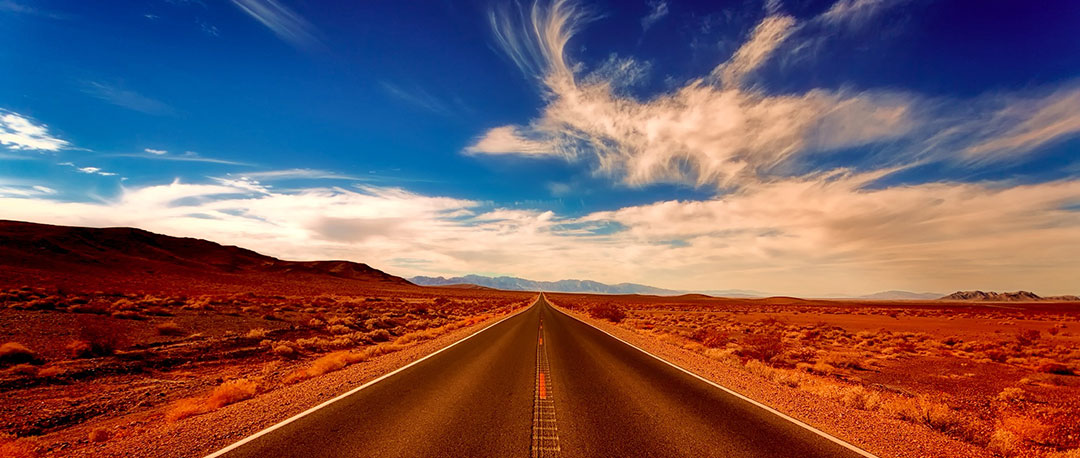 Eine Straße bis zum Horizont in dramatischer Landschaft